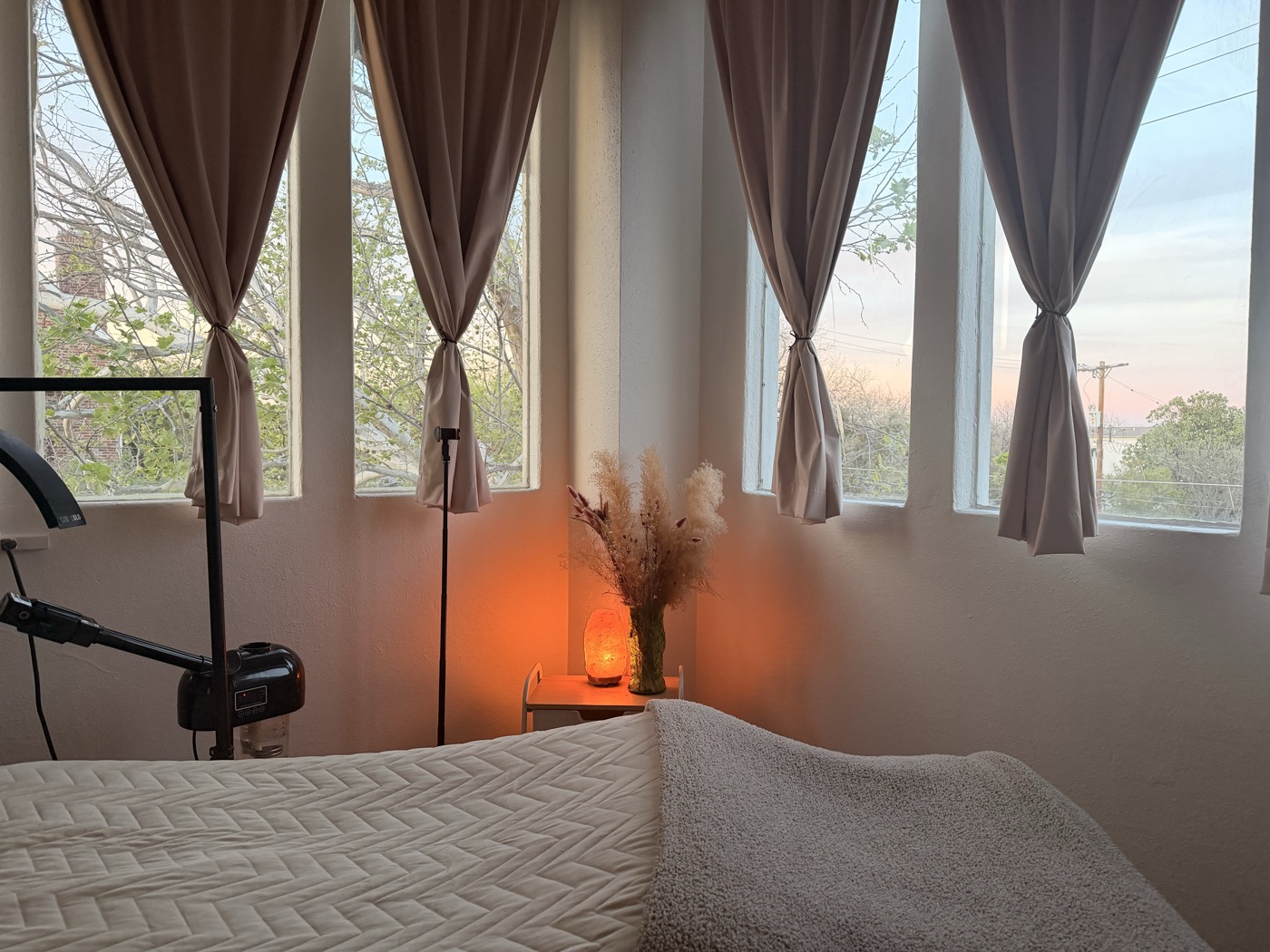 The TuneUp treatment room at golden hour, with tall windows onto the trees